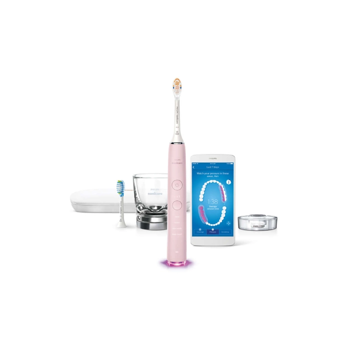 A pink electric toothbrush next to an electronic device.